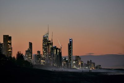 Illuminated modern buildings against sky during sunset