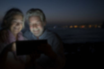 People holding mobile phone at night