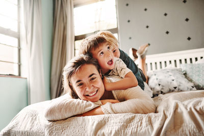 Portrait of smiling mother with kids lying on bed at home