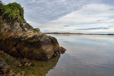 Rock formation on beach against sky