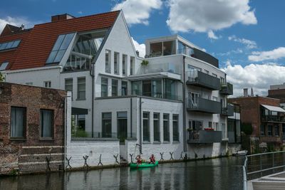 Buildings by river against sky in city