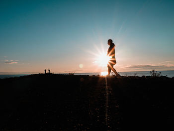 Silhouette people standing on land against sky during sunset