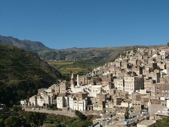 High angle view of buildings in city against clear blue sky