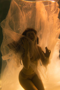 Woman with curtain swimming in pool