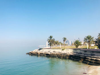 Swimming pool by sea against clear blue sky