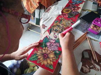 High angle view of woman drawing on cardboard