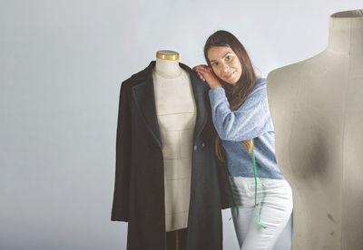 Portrait of young woman standing against wall