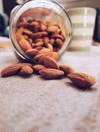 Close-up of almonds spilling from jar on table