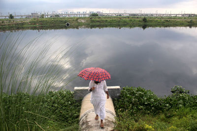 Woman with umbrella on field during rainy season