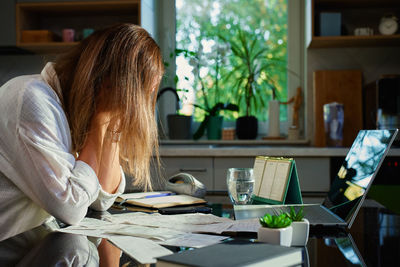 Midsection of woman using mobile phone while sitting on table