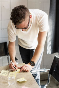 Young businessman writing adhesive notes on desk at new office