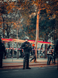 People walking on road against trees in city