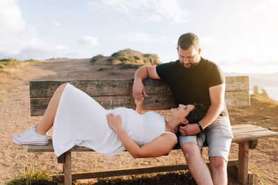 Full length of pregnant woman lying on bench with husband