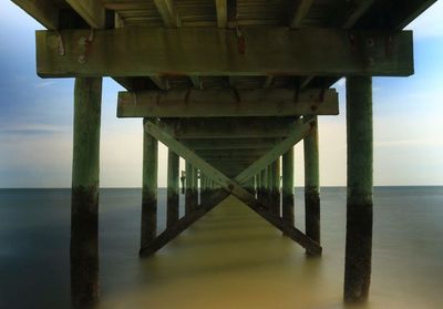 Pier over sea against sky during sunset