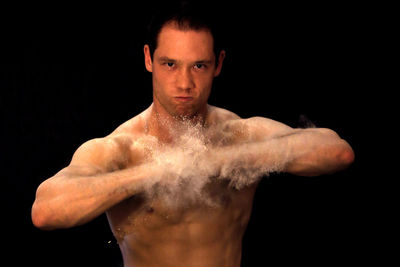 Portrait of shirtless man against black background