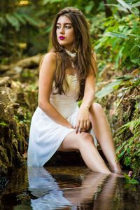 Portrait of beautiful young woman sitting by lake