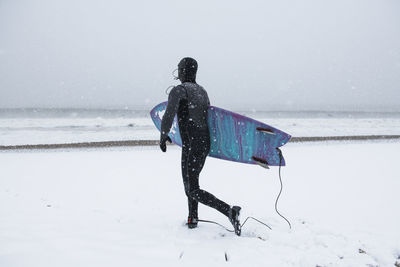 Man preparing to go surfing during winter snow