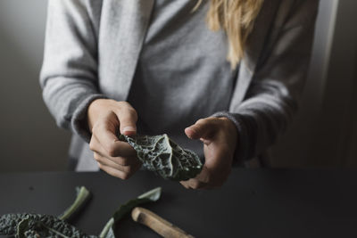 Midsection of woman holding green leaf