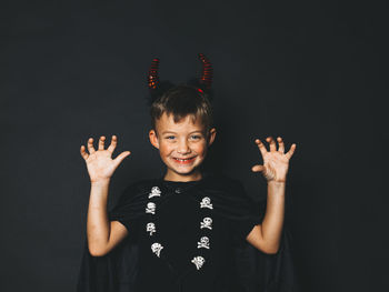 Portrait of boy standing against black background