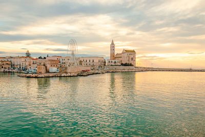 View of buildings at waterfront against cloudy sky