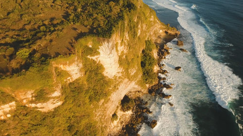 Aerial view rocky coast with surf waves at sunset, bali,indonesia, pura uluwatu cliff. 