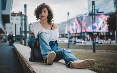 Portrait of young woman sitting in city