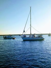 Sailboats sailing in sea against clear sky