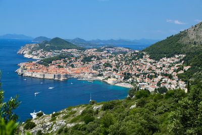 Aerial view of townscape by sea against sky