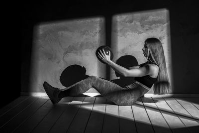 Woman exercising with equipment on floor against wall