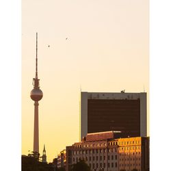 Communications tower in city against sky