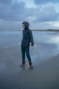 A teenager with a pensive face stands on the shore, looks to the side, a young man in full growth