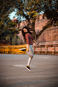 Full length of woman jumping against trees