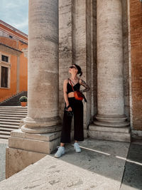 Full length of young woman standing against building