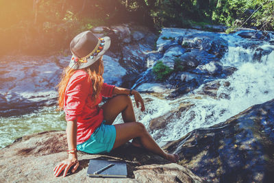 Side view of man sitting on rock