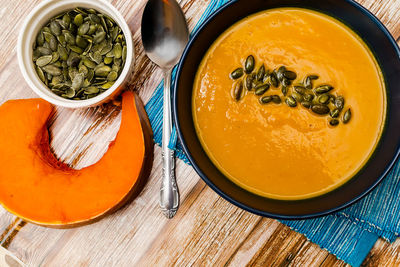 Cream pumpkin soup garnished with pumpkin seeds on a wooden table