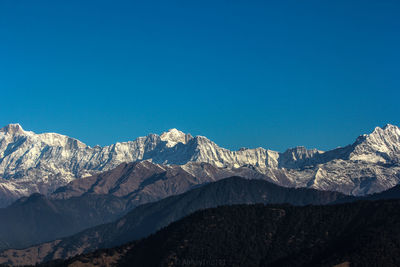 Scenic view of snowcapped mountains against clear blue sky