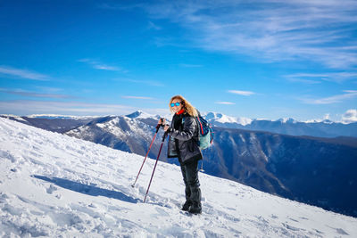 Rear view of man standing on snowcapped mountain against sky