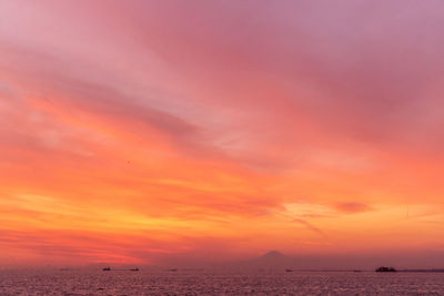 Scenic view of sea against dramatic sky during sunset