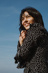 Smiling woman looking away against sky