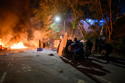 Group of people by fire on street at night