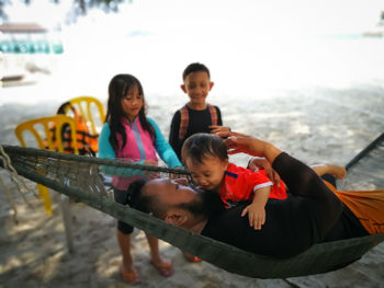 Father embracing daughter by siblings at beach