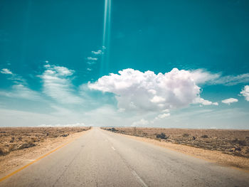 Country road amidst land against sky