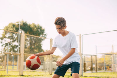 Boy playing basketball against clear sky