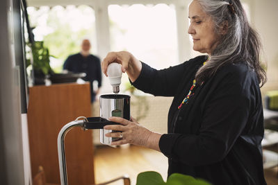 Senior woman changing bulb at home