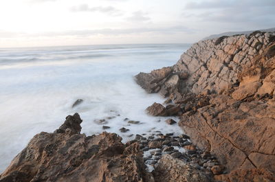 Scenic view of rocky beach against sky