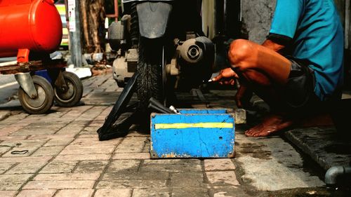 Low section of mechanic repairing motorcycle at auto shop