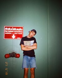 Portrait of young man standing against wall