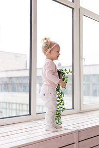 Portrait of young woman standing by window