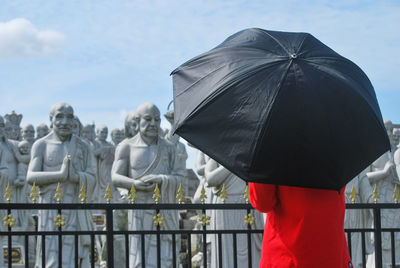 Man with umbrella standing against sculptures