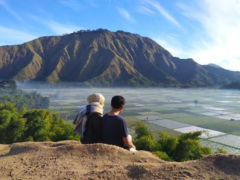 Rear view of people looking at mountains against sky